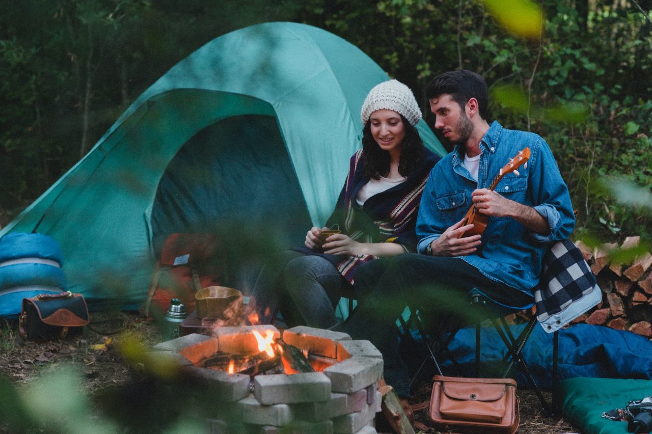 a couple enjoying bonfire with a guitar beside a tent in a Tanzania budget safari
