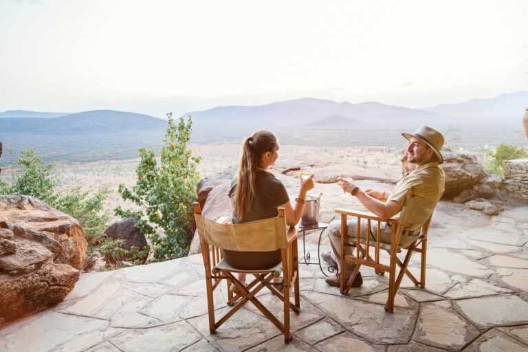 A couple having a cup of coffee at a scenic lodge viewpoint with panoramic views of Tanzania’s landscapes.