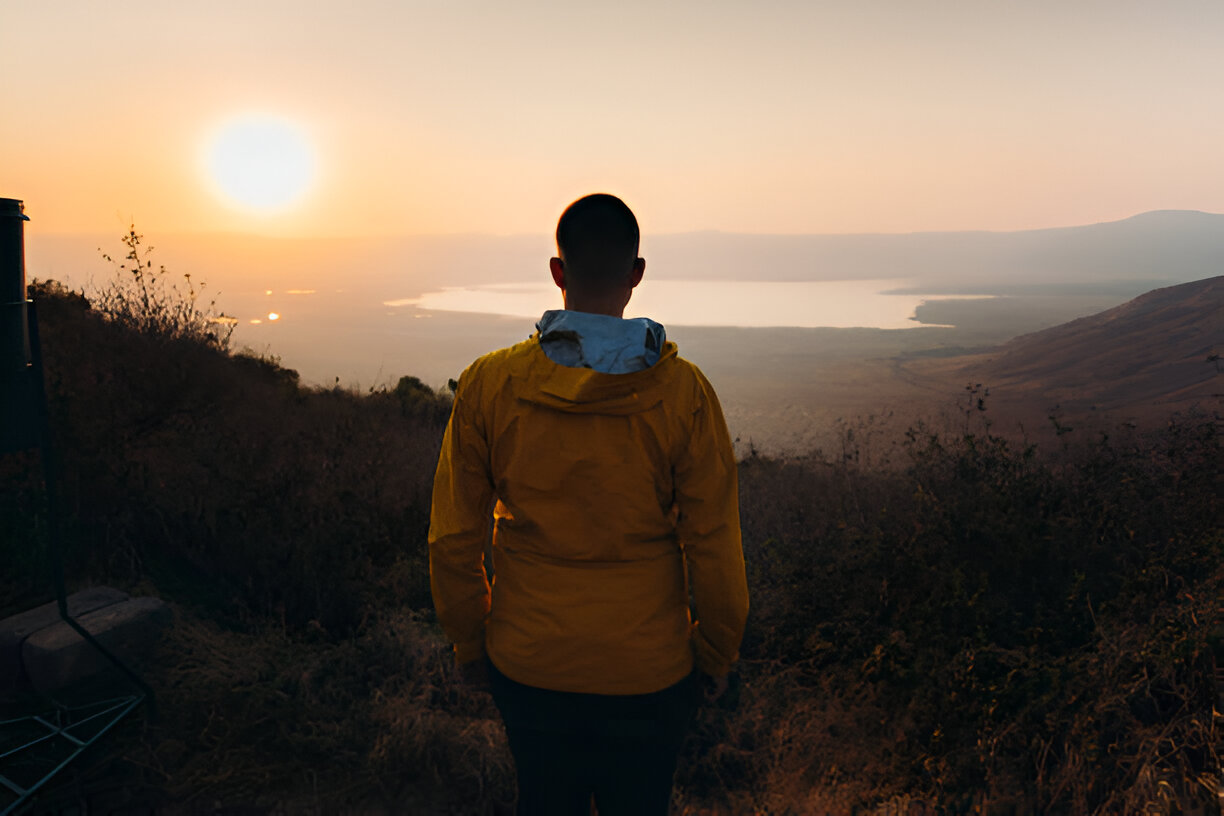 A tourist enjoying a sunrise view over Ngorongoro Crater from an elevated position, capturing Tanzania’s beauty