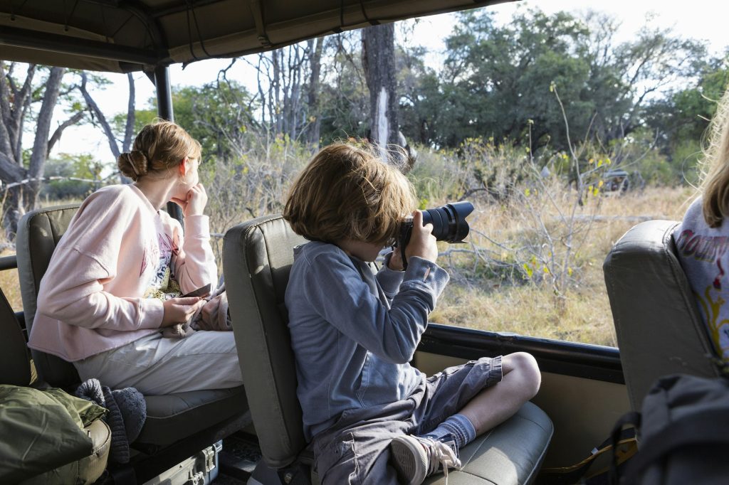 Young boy using a camera in a safari jeep