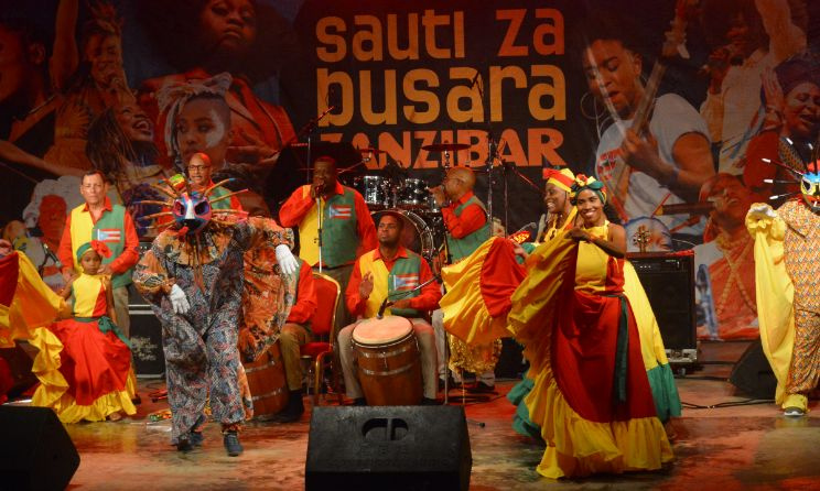 A group of performers in vibrant traditional attire, celebrating Tanzanian culture at the Sauti za Busara festival.