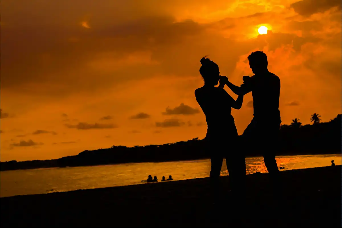 Honeymoon couple walking on white sandy Zanzibar beach at sunset