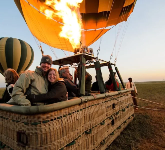 A hot air balloon being fired up on the ground at sunrise, preparing for an aerial Serengeti adventure.