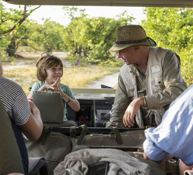 A family of visitors in a safari vehicle with a guide.