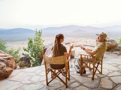 A couple having a cup of coffee at a scenic lodge viewpoint with panoramic views of Tanzania’s landscapes.