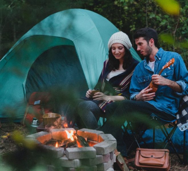 a couple enjoying bonfire with a guitar beside a tent in a Tanzania budget safari