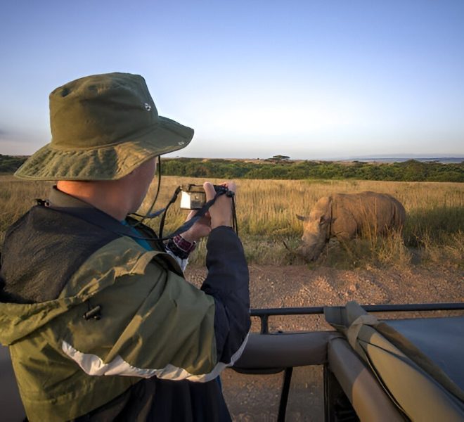 A photographer taking a close-up shot of a rhino during a Tanzania wildlife safari.